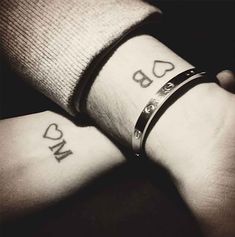 two people holding hands with tattoos on their wrists and wristbands that say love