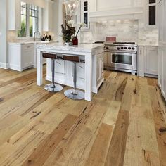 a large kitchen with white cabinets and wood flooring on the walls, along with an island in the middle