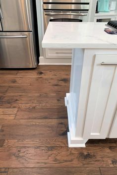 a kitchen with white cabinets and wood floors