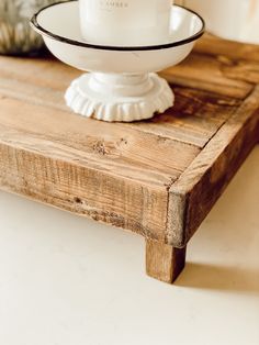 a white bowl sitting on top of a wooden table next to a glass candle holder