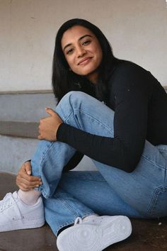 a woman is sitting on the steps with her legs crossed and looking at the camera