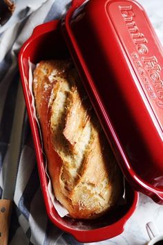 a red casserole dish with bread in it on a blue and white towel