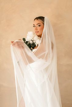 a woman wearing a veil and holding flowers