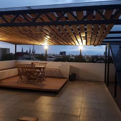 an outdoor patio with table and chairs under a pergolated roof at night time