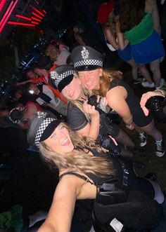 three women dressed in police uniforms posing for the camera at a party with other people