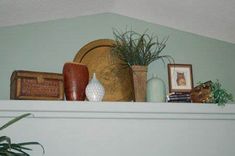 a shelf filled with vases and plants on top of a white mantle