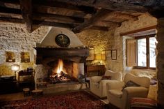 a living room with a fire place next to a couch and chair in front of a fireplace