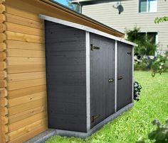 a small shed sitting in the grass next to a house