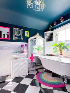 a white bath tub sitting inside of a bathroom next to a sink and toilet under a chandelier