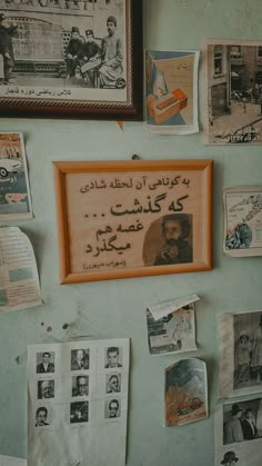 a wall covered in pictures and papers next to a framed sign with writing on it