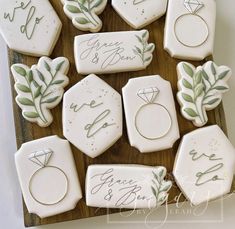 decorated cookies with wedding rings and leaves are on a wooden platter for guests to eat