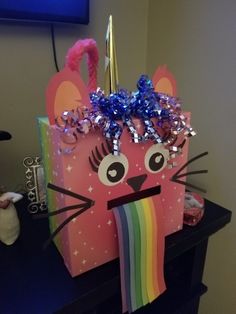 a pink bag with a cat face on it and a rainbow streamer in the mouth