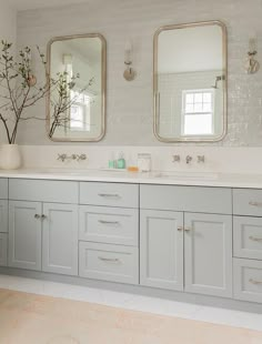 a bathroom with double sinks and two mirrors on the wall next to eachother