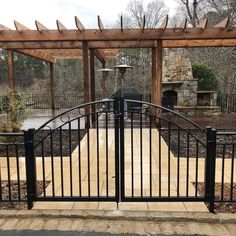 an iron gate is opened to reveal a patio with grill in the background and stone steps leading up to it