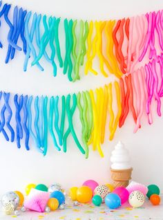 an ice cream cone is in the foreground with rainbow streamers hanging above it