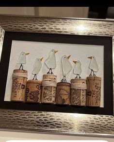 three birds sitting on top of corks in front of a framed photo with the words love