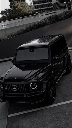 a black mercedes g - class parked in a parking lot next to a tall building