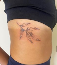 a woman's stomach with an olive branch tattoo on her side ribcage