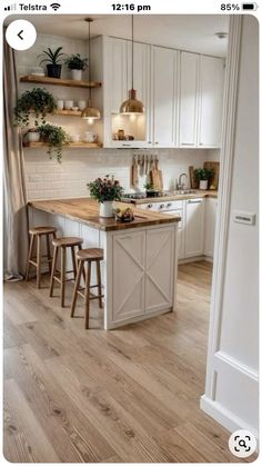 an open kitchen with white cabinets and wooden counter tops, along with two stools in front of the island