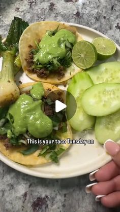 two tacos on a plate with cucumbers and green sauce