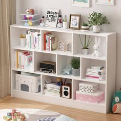 a white book shelf filled with lots of books next to a wall mounted art piece