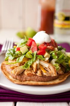 a white plate topped with an enchilada covered in lettuce and tomatoes