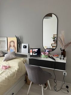 a bedroom with a bed, desk and mirror on the wall next to each other