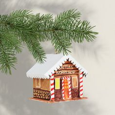 a christmas ornament hanging from a tree branch with a small house on it