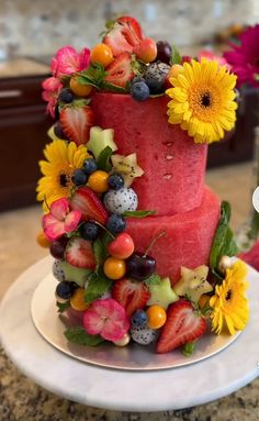 a three tiered cake covered in fruit and flowers