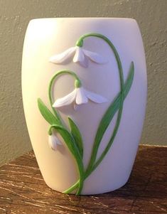 a white vase sitting on top of a wooden table