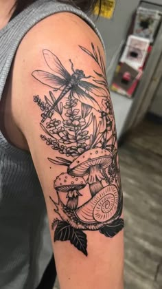 a woman's arm with a dragonfly and flowers tattoo on the left shoulder