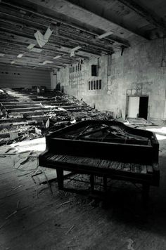 an old piano is sitting in the middle of a run down building with broken windows