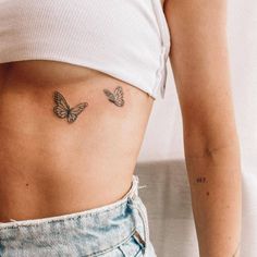 two butterflies on the side of a woman's stomach, both with small tattoos