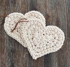 two crocheted hearts sitting on top of a wooden table