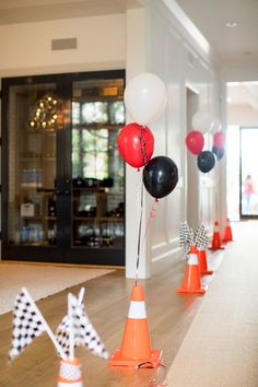 balloons and cones are lined up on the floor in front of an entrance to a party