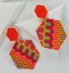 a pair of colorful beaded earrings sitting on top of a white plate