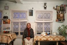 a woman sitting on a chair in front of a table covered with cloths and pictures