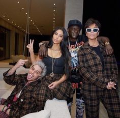 three people posing for the camera in front of a couch with one person on it's lap