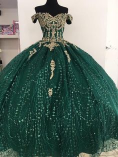 a green ball gown with gold detailing on the bust and shoulders, in front of a mannequin