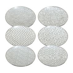 four white plates sitting on top of each other in different shapes and sizes, all with wavy designs