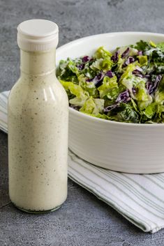 a salad in a bowl next to a bottle of dressing