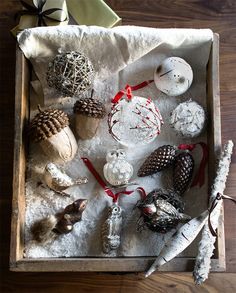 a box filled with assorted christmas ornaments on top of a wooden floor covered in snow