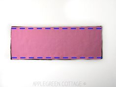 a piece of pink paper with blue stitching on the edge is laying on a white surface