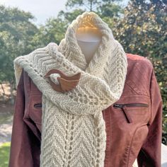 a white knitted scarf hanging on a mannequin's dummy outside in the sun