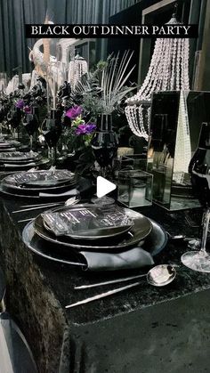 a table set up for a black out dinner party with silverware and crystal chandeliers