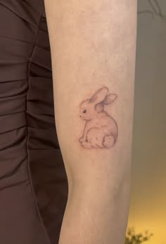 a woman's arm with a small tattoo of a rabbit on the left side