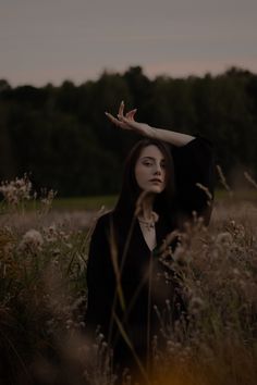 a woman standing in tall grass with her hands on her head