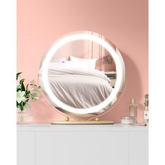 a round mirror sitting on top of a white dresser next to a vase with flowers