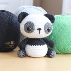 two balls of yarn and a stuffed panda bear on a table next to each other