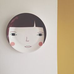 a white plate with a face on the wall next to a brown and yellow wall